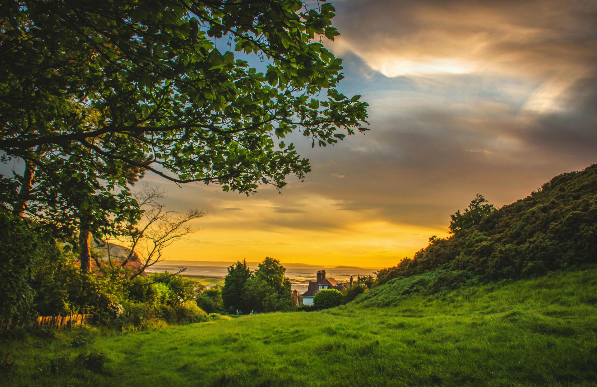 A picturesque sunset over the lush, green countryside of Deganwy, Wales, capturing nature's beauty.