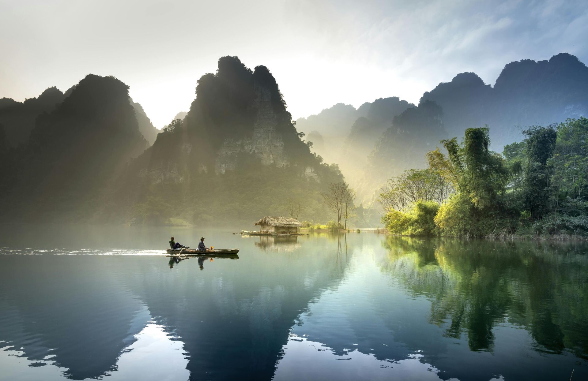Tranquil lake with mountains reflecting at sunrise in Tuyên Quang, Vietnam.