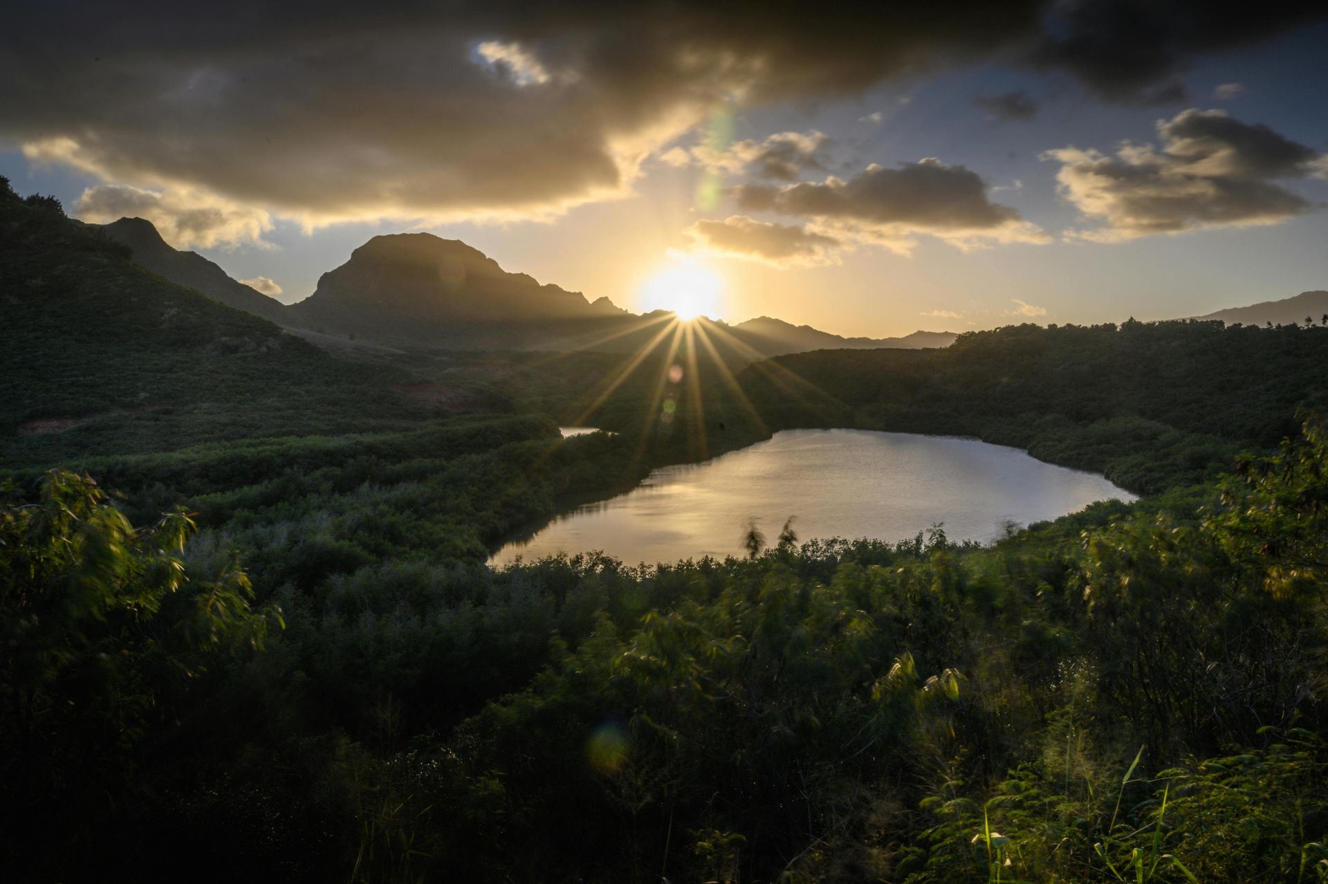 Capture the breathtaking sunrise over a tranquil mountain lake in Hawaii, surrounded by lush greenery.