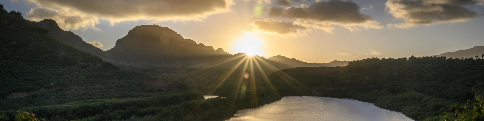 Capture the breathtaking sunrise over a tranquil mountain lake in Hawaii, surrounded by lush greenery.