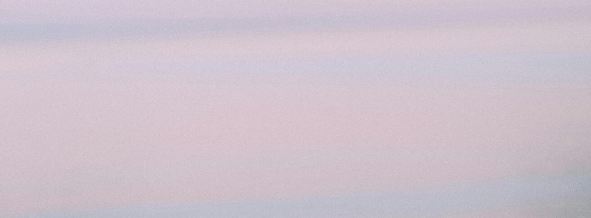 Closeup of multiracial hands holding, symbolizing unity and equality against a serene sky.